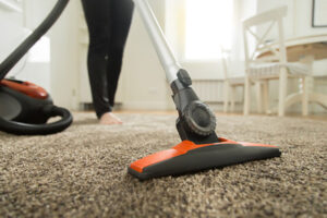 Image of homeowner using a vacuum to remove pet odor from carpet