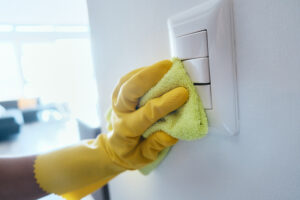 Person with gloves sanitizing switches and handles