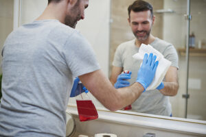 Man cleaning mirror in the bathroom